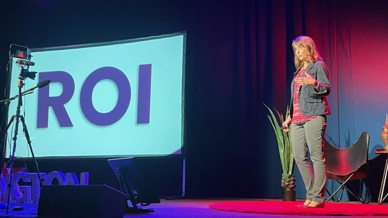 Teresa Huff on the TEDx stage beside a slide reading ROI, video preview